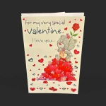 Recto de la carte Saint-Valentin ourson rouge Genève avec un adorable ourson gris tenant une rose au milieu de cœurs.