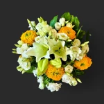 Gros plan sur le bouquet lumineux geneve 'Le retour du soleil', avec ses lys blancs majestueux et ses renoncules jaune-or.