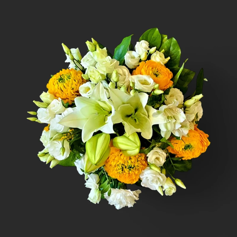 Gros plan sur le bouquet lumineux geneve 'Le retour du soleil', avec ses lys blancs majestueux et ses renoncules jaune-or.