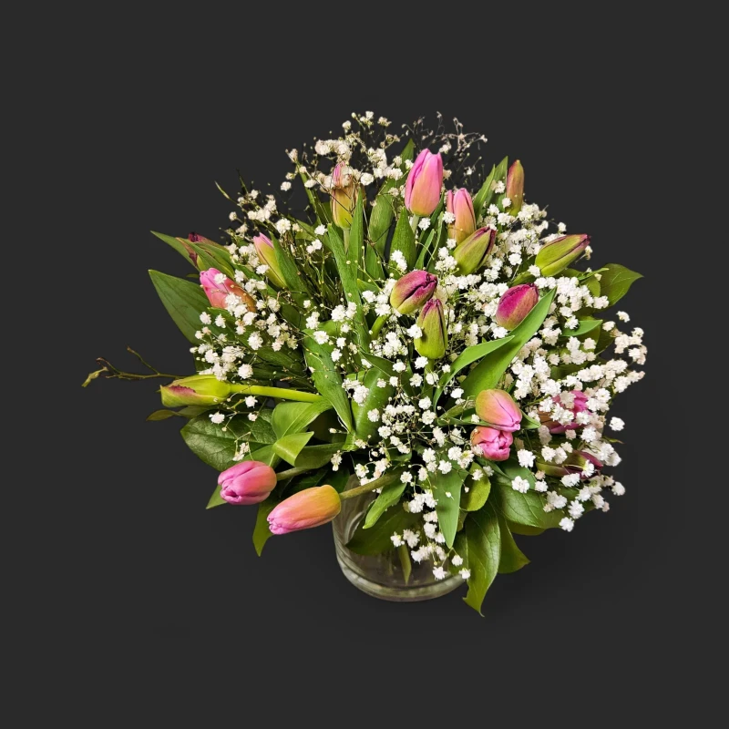 Sublime bouquet tulipes roses gypsophile geneve dans son vase en verre facetté, mettant en valeur ses boutons sur fond noir.