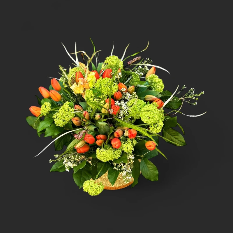 Gros plan sur le bouquet tulipes corail viorne genève dans son panier tressé, montrant l'éclat des fleurs colorées.
