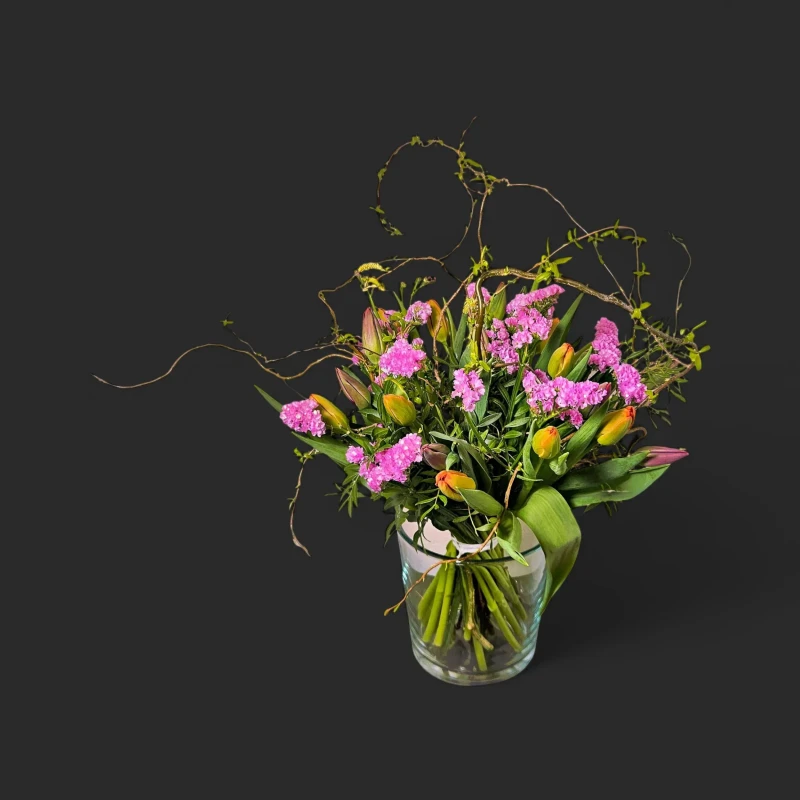 Le bouquet tulipes saule printemps geneve "Osier en Bouton", avec ses tulipes orangées et son saule dans un vase en verre.