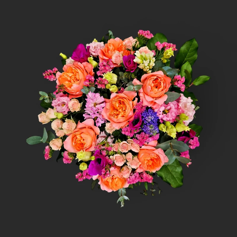 Gros plan sur un bouquet corail roses printemps genève luxuriant, avec des roses anglaises, anémones fuchsia et jacinthes.