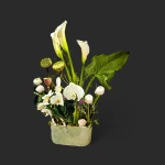 Élégante composition florale blanche geneve avec arums élancés, orchidées nacrées et capsules de lotus sur fond noir.