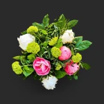 Gros plan sur un bouquet pivoines viorne genève, avec des pivoines roses et ivoire et des fleurs de viorne vertes sur fond noir.
