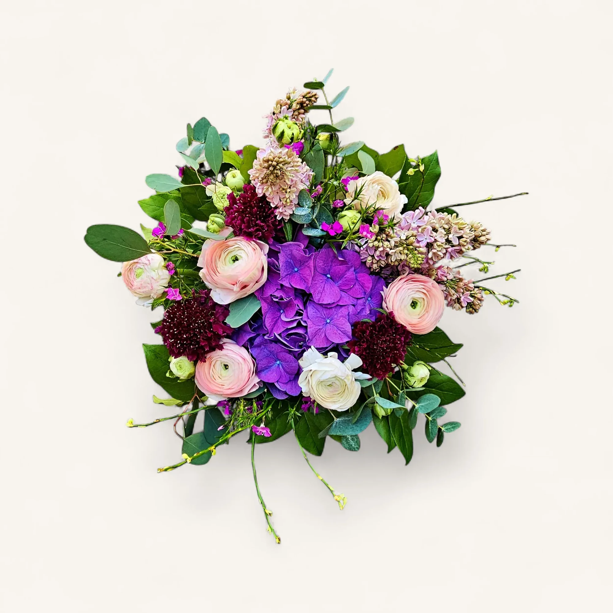 JTNE-7.webp Vue rapprochée du bouquet hortensia renoncules pastel genève, Amarante Céleste, avec son cœur d'hortensia violet et ses fleurs délicates.