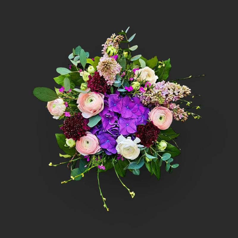 Vue rapprochée du bouquet hortensia renoncules pastel genève, Amarante Céleste, avec son cœur d'hortensia violet et ses fleurs délicates.