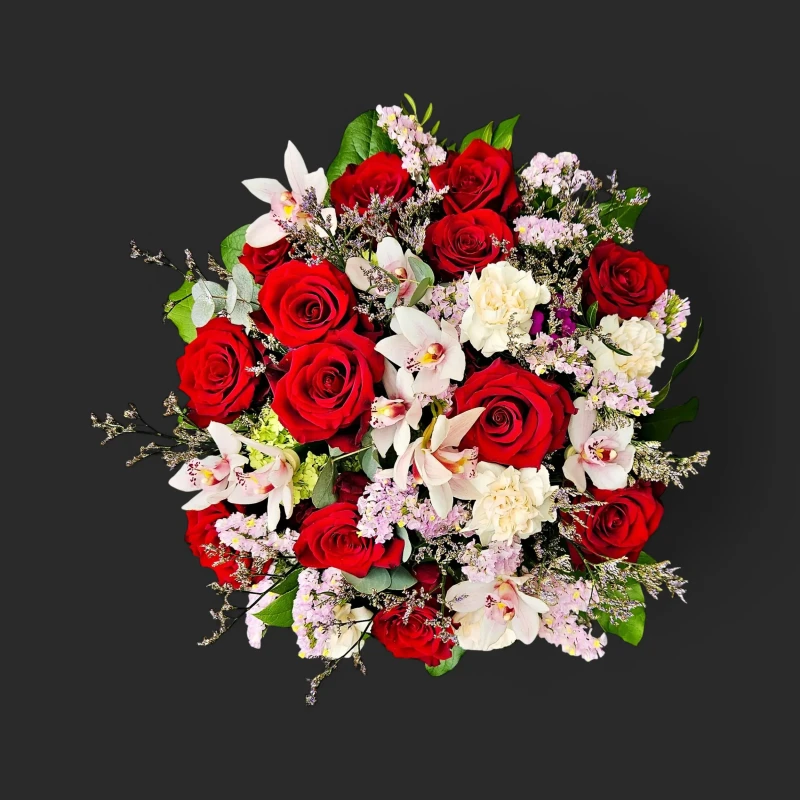 Luxueux bouquet roses rouges geneve 'Rubis de Mai' avec orchidées cymbidium blanches et œillets sur un fond noir contrastant.