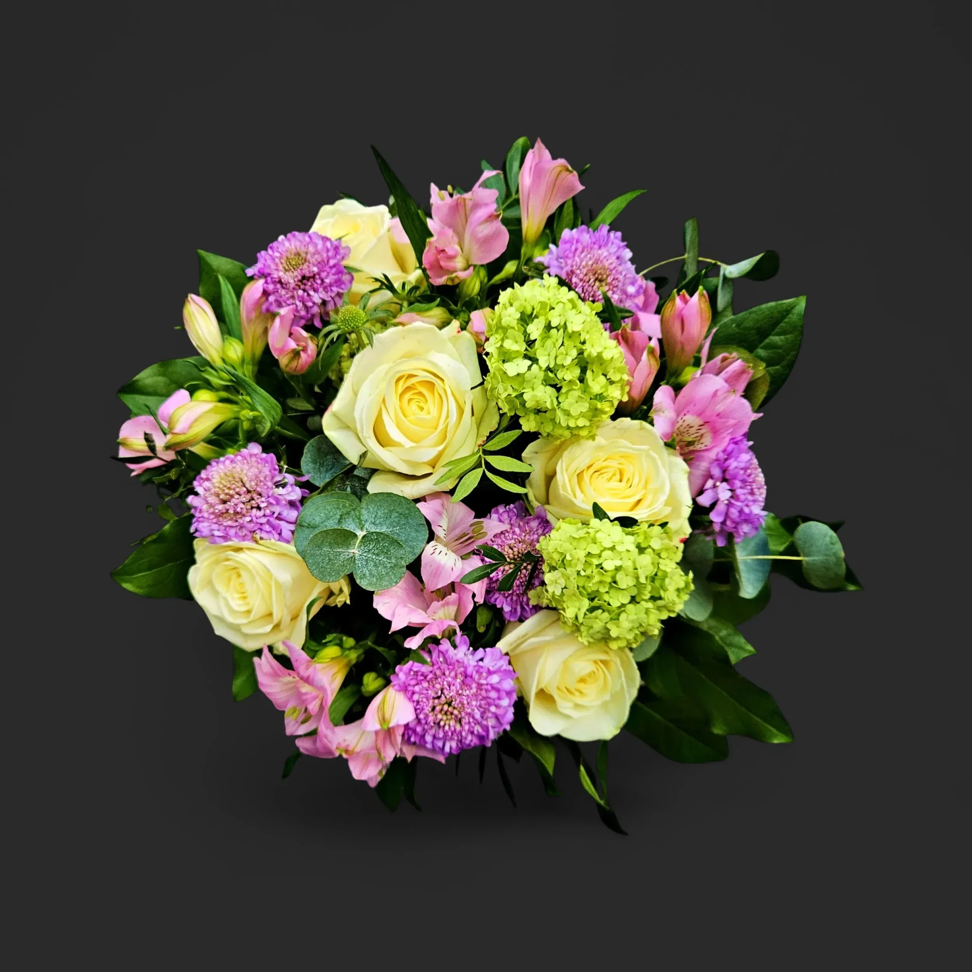 eU0lM0Q.webp Gros plan du bouquet roses ivoire hortensia genève, composition pastel avec pompons violets et alstroemères roses sur fond noir.