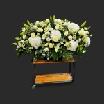 Fleurs deuil Genève dessus de cercueil blanc, roses, hortensias et lys en boutons dans un bac noir
