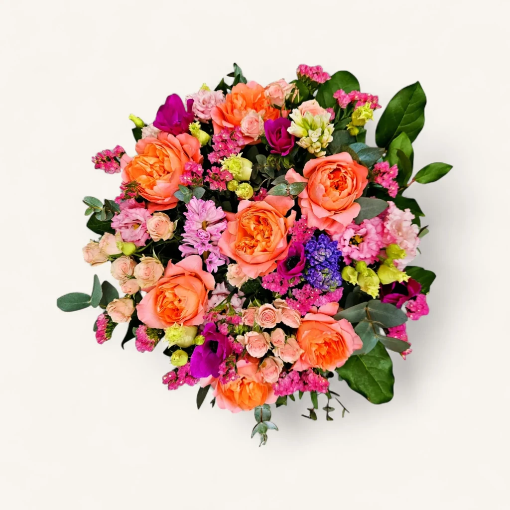 Gros plan sur un bouquet corail roses printemps genève luxuriant, avec des roses anglaises, anémones fuchsia et jacinthes.